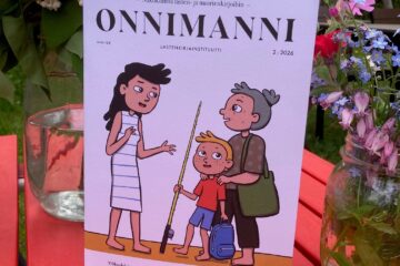 Onnimanni-lehti punaisella pöydällä.